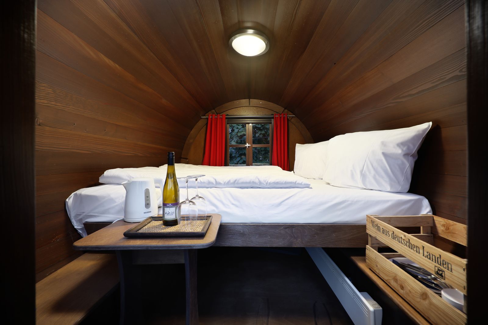 Innenansicht Weinfass — Doppelbett mit weißer Bettwäsche, Holzdecke, Weinflasche zur Begrüßung